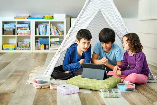 Siblings enjoying tablet time inside a play tent