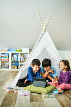 Children Engaged in Creative Play with Beads and Tablet