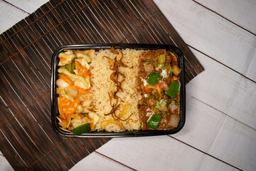 Chicken tikka masala with pulao biryani rice with cucumber, dip sauce and lemon slice served in dish isolated on wooden table top view closeup of bangladeshi and indian spicy lunch food
