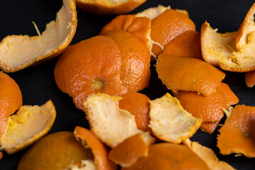 a large number of orange citrus fruits on a black slate surface