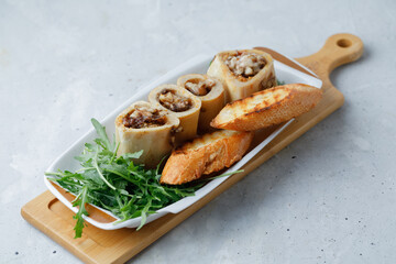 Homemade Roasted Beef Bone Marrow with croutons on plate, wooden board grey background. Top View.