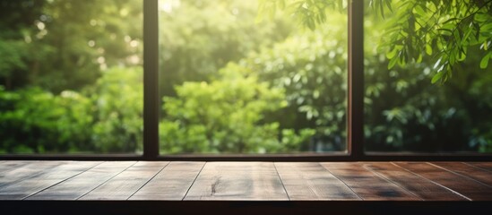 Blurred interior room with window view from green tree garden on empty wood table top