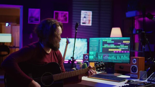 Young Man Songwriter Playing Guitar And Creating Music Using Equalizer Program. Musician Recording Song In Home Studio, Engineer Mixing And Mastering Pop Rock Tracks. Camera B.