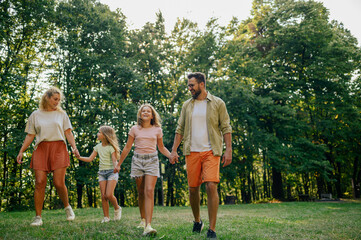 Fototapeta premium A happy family is walking in nature on meadow while holding hands.