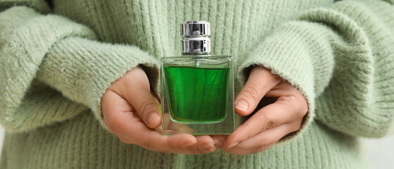 Young woman with bottle of perfume, closeup
