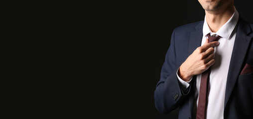 Young man in stylish suit on dark background