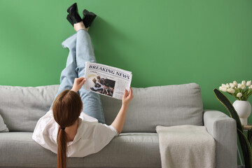 Young woman reading newspaper at home after long working day