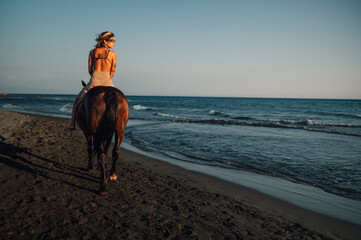 Rear view of a horsewoman riding a horse at the beach.