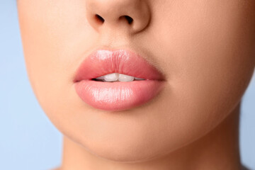 Young woman with beautiful lips on blue background, closeup