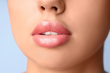 Fototapeta premium Young woman with beautiful lips on blue background, closeup