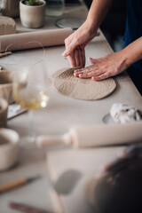 Close up of pottery class teacher showing shaping wet clay in studio.