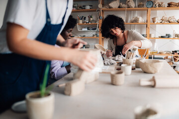 Interracial pottery class students making handcrafts and clay work.