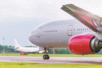 The planes lined up on the taxiway, awaiting clearance from the control tower. The main character of the photo, an airplane with a bright red engine, demonstrates the scale of aircraft technology