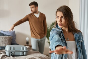 Fototapeta premium A man and a woman standing in a bedroom, engaged in a heated argument during their vacation.