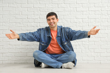 Young man opening arms for hug near white brick wall