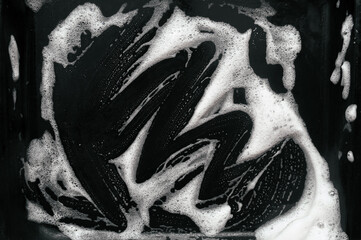Texture of white foam and soap on a dark background. Abstract pattern. Concept of washing an oil...
