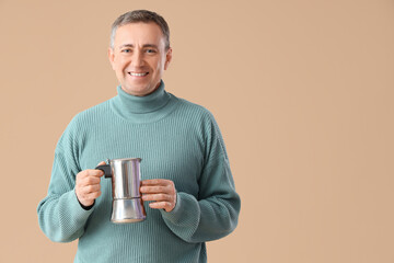 Mature man with geyser coffee maker on beige background