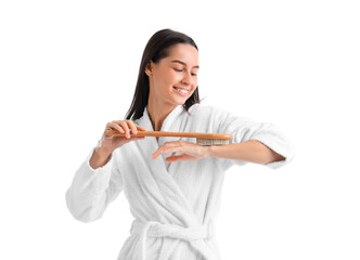 Young woman in bathrobe massaging arm on white background