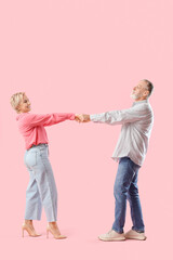 Mature couple dancing on pink background