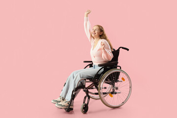 Young redhead woman in wheelchair on pink background