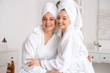 Young woman with her mother after shower hugging in bathroom