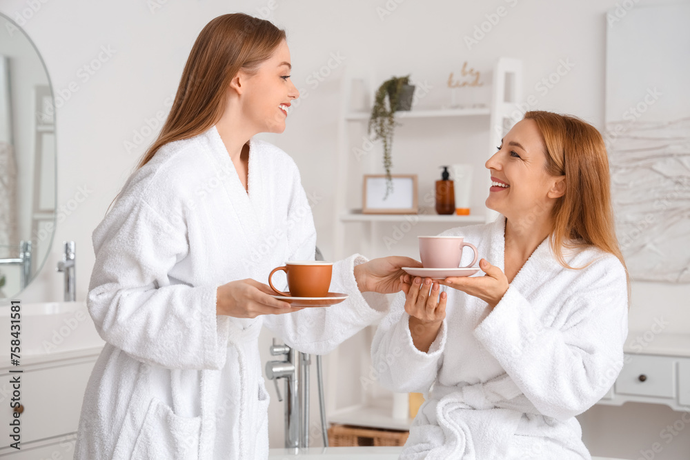 Poster Young woman with her mother drinking coffee after shower in bathroom