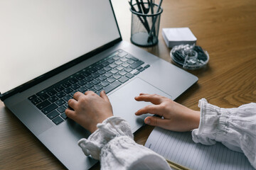 Blank laptop screen and student's hands, study concept