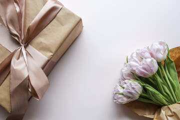Bouquet of pink tulips and a gift box with a bow, festive concept