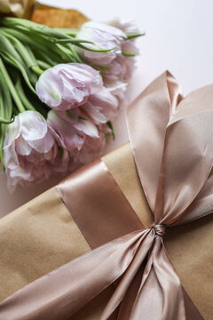 Bouquet of pink tulips and a gift box with a bow, festive concept