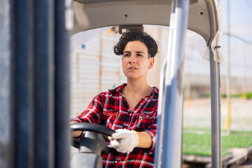 Chilean woman forklift worker operator driving vehicle at farm greenhouse