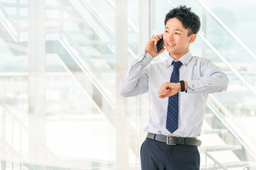 オフィスビルでスマホで電話する若いアジア人ビジネスマン
