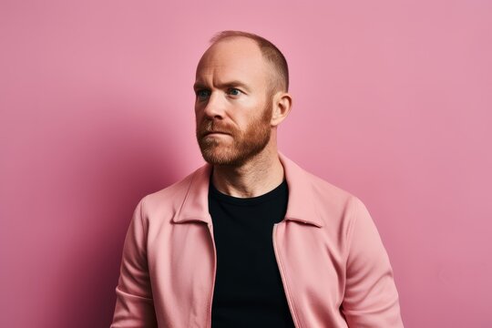 Portrait of a stylish man in a pink jacket on a pink background.