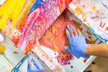 Young Asian generation z man learning acrylic pouring art on canvas workshop at art studio. Happy people artist enjoy and fun indoor hobbies creating colorful abstract modern art painting in class.