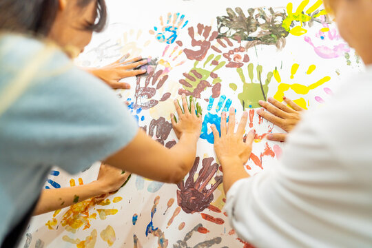Group of Asian generation z people learning acrylic painting art by hand on canvas workshop at art studio. Young artist university student enjoy and fun creating colorful abstract modern art in class.