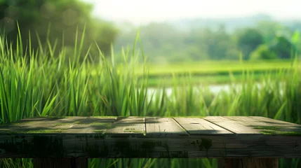 Deurstickers A wooden table sits in the midst of a lush meadow, surrounded by a vibrant natural landscape filled with terrestrial plants and grasses © Oleksandra