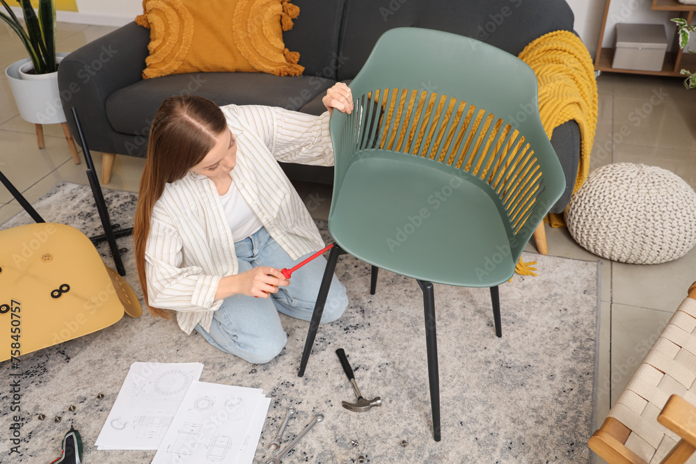 Wall mural Beautiful young woman with manual and screwdriver assembling furniture at home