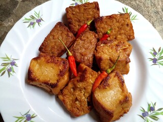 Tempeh tahu bacem. Tempeh and tofu are boiled with spices and brown sugar until absorbed and then fried. Tempeh and bacem tofu have a sweet taste. Typical food from Java, Indonesia. Closeup photo.