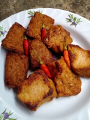 Tempeh tahu bacem. Tempeh and tofu are boiled with spices and brown sugar until absorbed and then fried. Tempeh and bacem tofu have a sweet taste. Typical food from Java, Indonesia. Closeup photo.