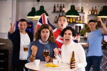 Group of people with UK flag toasting with beer, having fun at party in nightclub