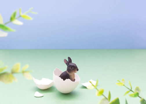 Minimal Easter card with a bunny hatching from an egg framed by green leaves. Holiday spring card. Selective focus, copy space