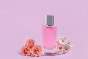 Pink bottle of perfume and flowers on purple background