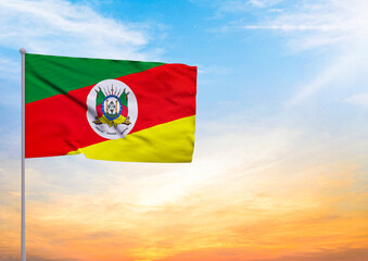 3D illustration of a Rio Grande do Sul flag extended on a flagpole and in the background a beautiful sky with a sunset