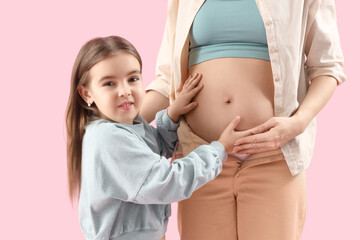 Little girl with her pregnant mother on pink background
