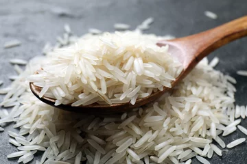 Fotobehang Raw basmati rice and wooden spoon on black table, closeup © New Africa