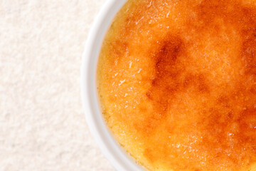 Delicious creme brulee in bowl on light textured table, top view. Space for text