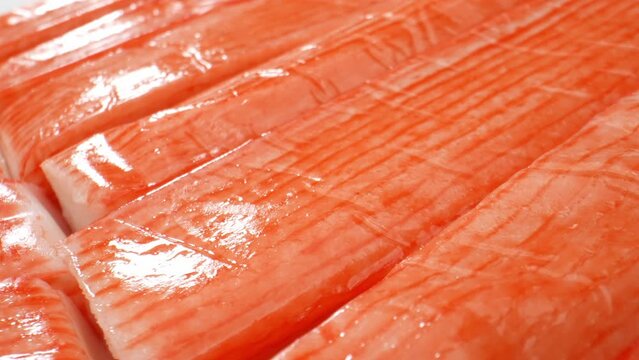 Crab sticks mimic real crab's flavor and appearance, with a slightly firmer texture. They're versatile, used in salads, sushi, sandwiches, soups, stir-fries, and seafood pasta. Food concept. 4K HDR. 