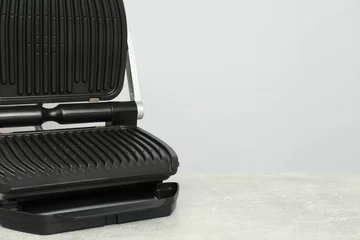 Fotobehang Electric grill on textured table against grey background, space for text. Cooking appliance © New Africa