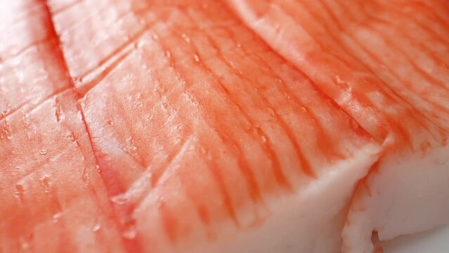 Crab sticks are made by grinding fish meat with starch, egg whites, flavorings, and sometimes crab extract. The mixture is shaped into sticks, cooked, cooled, and packaged for sale. Food concept. 4K.