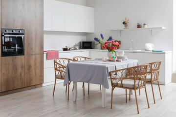 Dining table with Easter eggs, tulips and dinnerware in kitchen