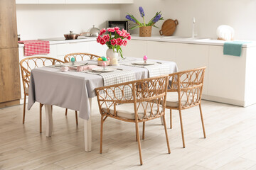 Dining table with Easter eggs, tulips and dinnerware in kitchen